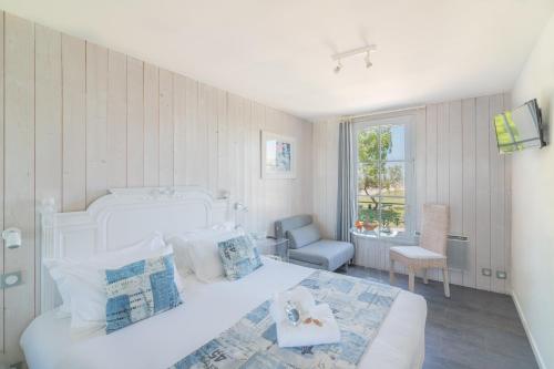 a white bedroom with a large bed and a chair at Le Clos Du GALION - Ile de Ré in Saint-Martin-de-Ré