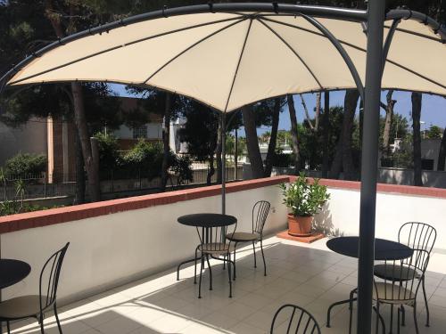 a patio with tables and chairs under an umbrella at Villa Iavernaro in Pulsano