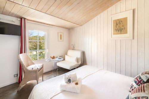 a bedroom with a bed and a chair and a table at Le Clos Du GALION - Ile de Ré in Saint-Martin-de-Ré