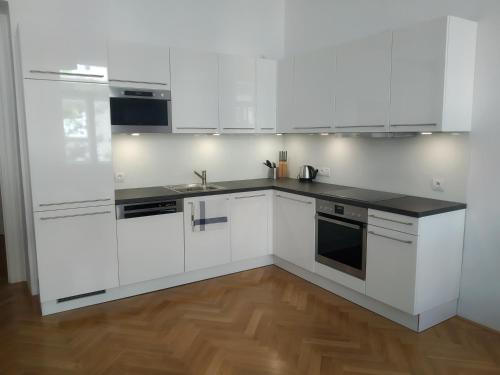 a white kitchen with white cabinets and a wooden floor at Prague Saints Apartments in Prague