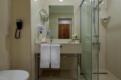 a bathroom with a sink and a shower with towels at Ramada By Wyndham Cappadocia in Ortahisar