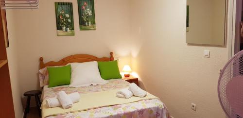 Dormitorio pequeño con cama con almohadas verdes y blancas en Calle Frailes Apartamento en Granada