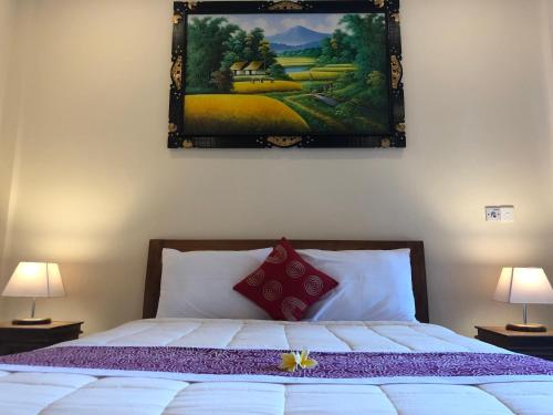 a bedroom with a bed with a painting on the wall at Taman Indah Homestay in Ubud