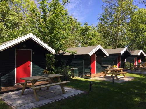 a group of lodges with picnic tables in the grass at Camping Engelbert (Groningen) in Groningen