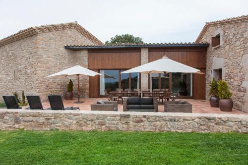 a patio with umbrellas and chairs and tables at El Porxo de Mateus in Sagás