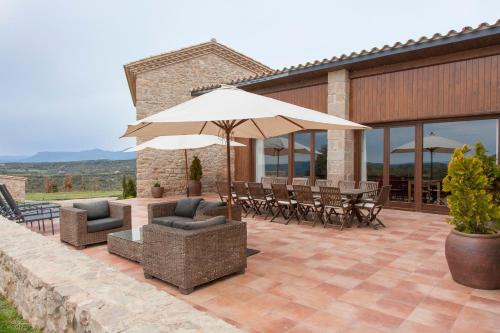 a patio with a table and an umbrella and chairs at El Porxo de Mateus in Sagás