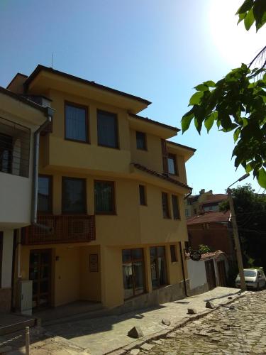 a large yellow building with windows on a street at Roots Hotel Old Town in Plovdiv