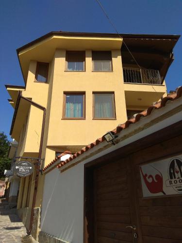 a yellow building with a garage in front of it at Roots Hotel Old Town in Plovdiv