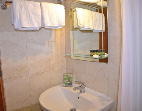 a bathroom with a sink and a mirror and towels at Sofia Hotel in Tolo