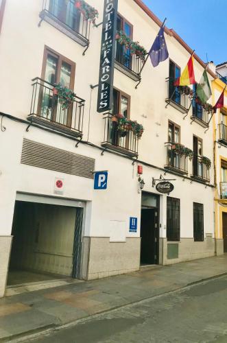 a white building with balconies and flags on a street at Hotel de Los Faroles in Córdoba