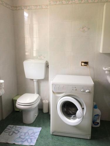 a bathroom with a toilet and a washing machine at Acero Rosso in San Colombano