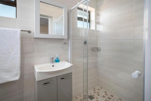 a white bathroom with a sink and a shower at Steenbok House in Hermanus