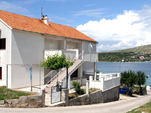 uma casa branca com escadas ao lado da água em Charming Apartment in Greba tica with Terrace em Grebaštica