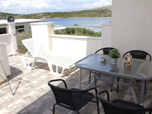 um pátio com uma mesa e cadeiras e vista para a água em Charming Apartment in Greba tica with Terrace em Grebaštica