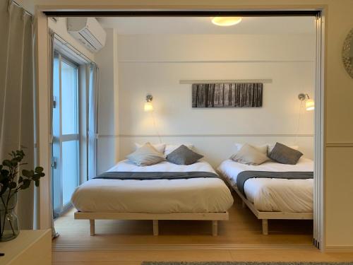 two beds in a room with a mirror at Allstay CHIBANA in Okinawa City