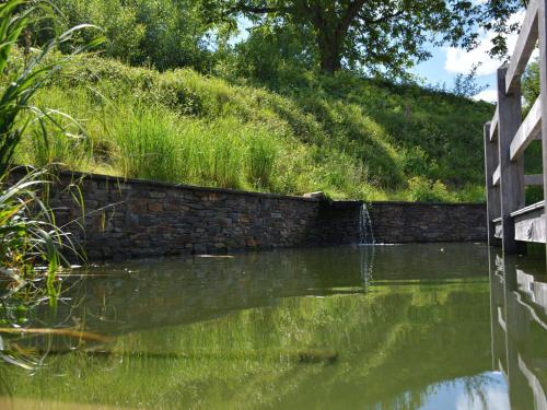 a pond with a stone wall and a water fountain at Holiday Home in Bièvre with Terrace in Bièvre