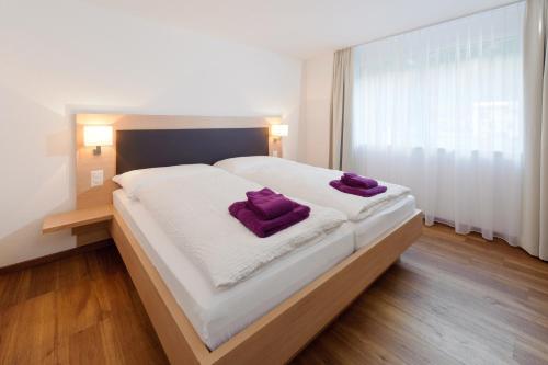um quarto com uma cama grande e almofadas roxas em Andolla em Saas-Almagell