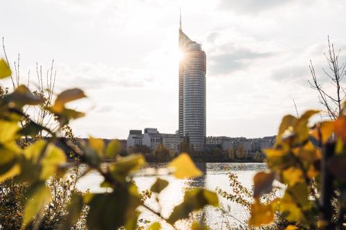 a tall building in front of a river with yellow flowers at harry's home hotel & apartments in Vienna