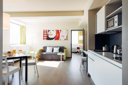 a kitchen and living room with a table and a couch at harry's home Wien hotel & apartments in Vienna