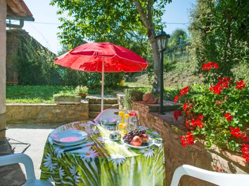 a table with a red umbrella and a plate of food at Apartment Il Mirto by Interhome in La Collina