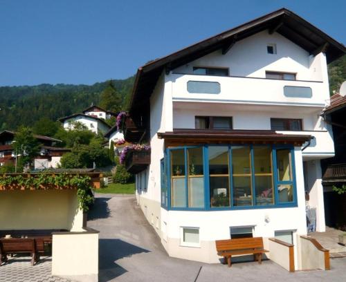 un edificio blanco con bancos delante en Pension Schöpf, en Arzl im Pitztal