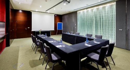 a conference room with tables and chairs and a white screen at Hyatt Regency Barcelona Tower in Hospitalet de Llobregat