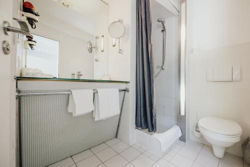 a white bathroom with a toilet and a shower at Magni Boutique Hotel in Braunschweig