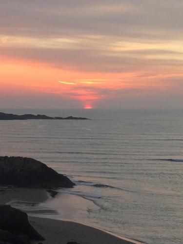 a sunset over the ocean with a sandy beach at Dolmen Cottage in Glencolumbkille