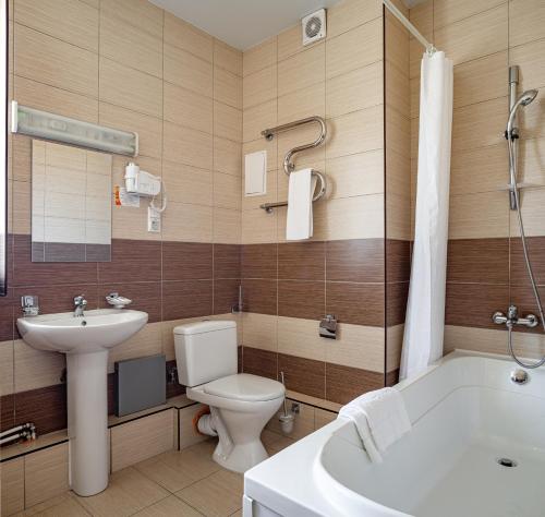 a bathroom with a toilet and a sink and a tub at Barkhatnye Sezony Sportivny Kvartal Resort in Adler