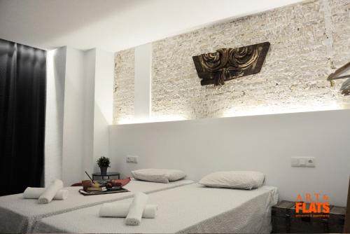 two beds in a room with a brick wall at Art&Flats Hostel in Valencia