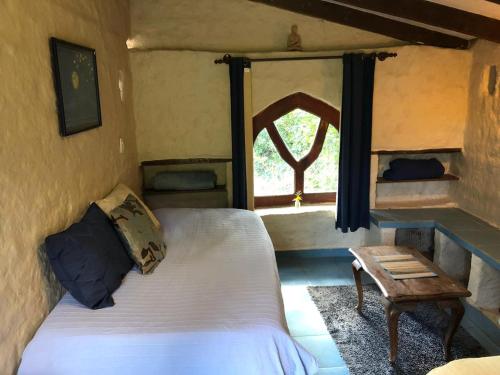 a bedroom with a bed and a window and a table at Quinta Conciencia in Samaipata