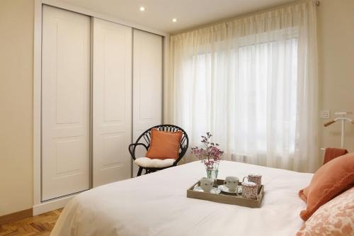 a bedroom with a bed and a chair and a window at Apartamento Ravachol Pontevedra ciudad in Pontevedra