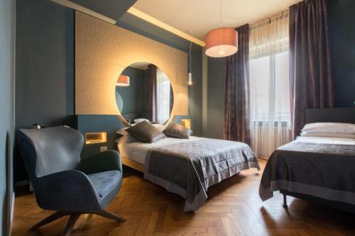 een slaapkamer met een bed, een stoel en een spiegel bij Le Texture Premium Rooms Duomo-Cordusio in Milaan