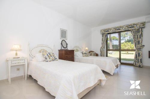 a bedroom with two beds and a window at Villa Joselina in Vilamoura
