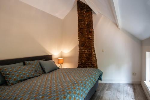 a bedroom with a bed and a brick wall at Vakantiehuis Hana in Heers