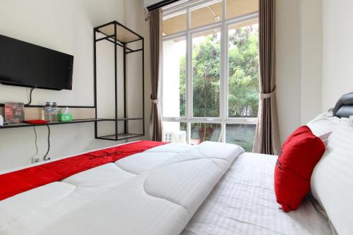 a bedroom with a red and white bed with a window at RedDoorz near Jogja City Mall 3 in Sleman