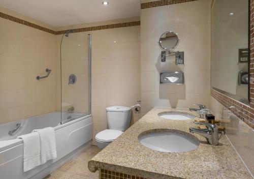 a bathroom with two sinks and a tub and a toilet at Bonnington Hotel & Leisure Centre in Dublin