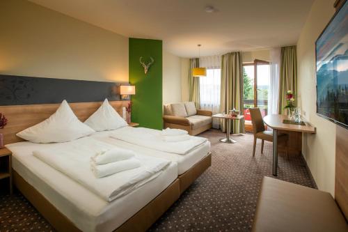 ヴァルダハタールにあるHotel Waldachtalの大きなベッドとリビングルームが備わるホテルルームです。