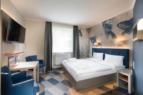 una camera con letto, scrivania e TV di Hotel Godewind a Warnemünde
