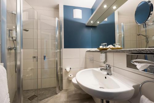 ein Bad mit einem Waschbecken und einer Dusche in der Unterkunft Hotel Godewind in Warnemünde