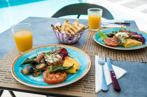two plates of food on a table with two glasses of orange juice at Evdokia Suites in Gouves