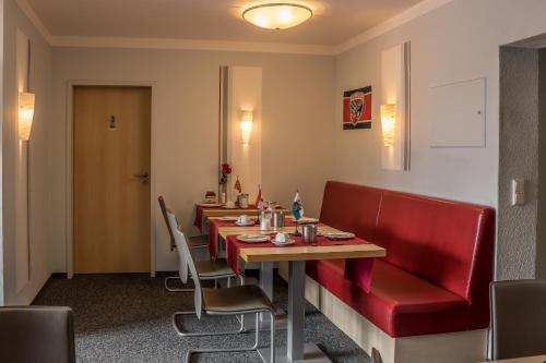 un restaurante con una mesa larga y sillas rojas en Pension Torkel-Stube en Ingolstadt