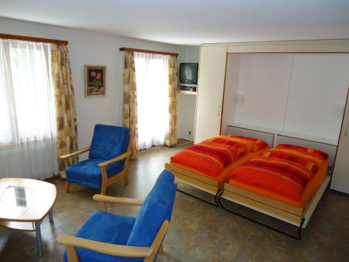 1 dormitorio con 1 cama grande y sillas azules en Haus Rio en Saas-Fee