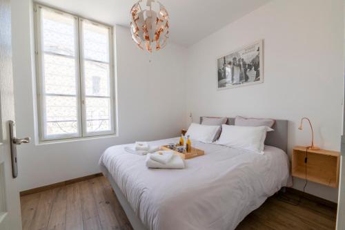 a bedroom with a large white bed with a tray on it at Le 25, appartement moderne au cœur de Saint-Emilion in Saint-Émilion