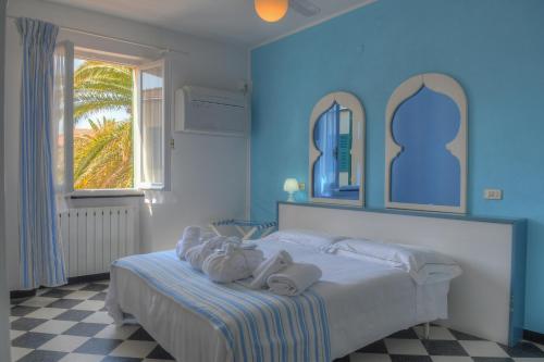 a blue bedroom with a bed with towels on it at Hotel Arabesque in Varigotti