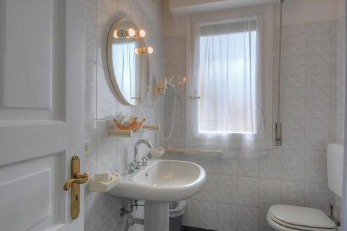a bathroom with a sink, toilet and mirror at Hotel Arabesque in Varigotti