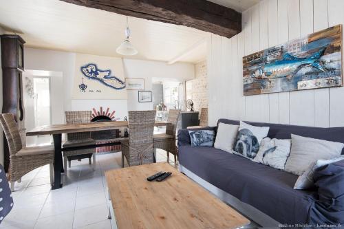 een woonkamer met een blauwe bank en een tafel bij Maison Aumière in La Flotte