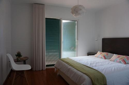 een slaapkamer met een bed, een stoel en een raam bij Freda House in Funchal