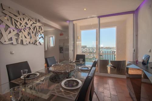 uma sala de jantar com uma mesa de vidro e vista em Duplex Marina de Vilamoura em Vilamoura
