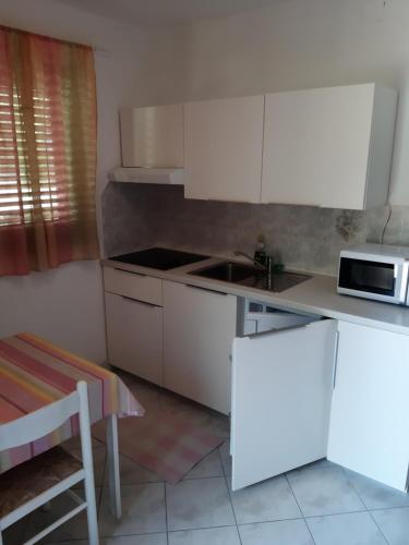a kitchen with white cabinets and a sink and a microwave at Apartments Juretic in Drenje